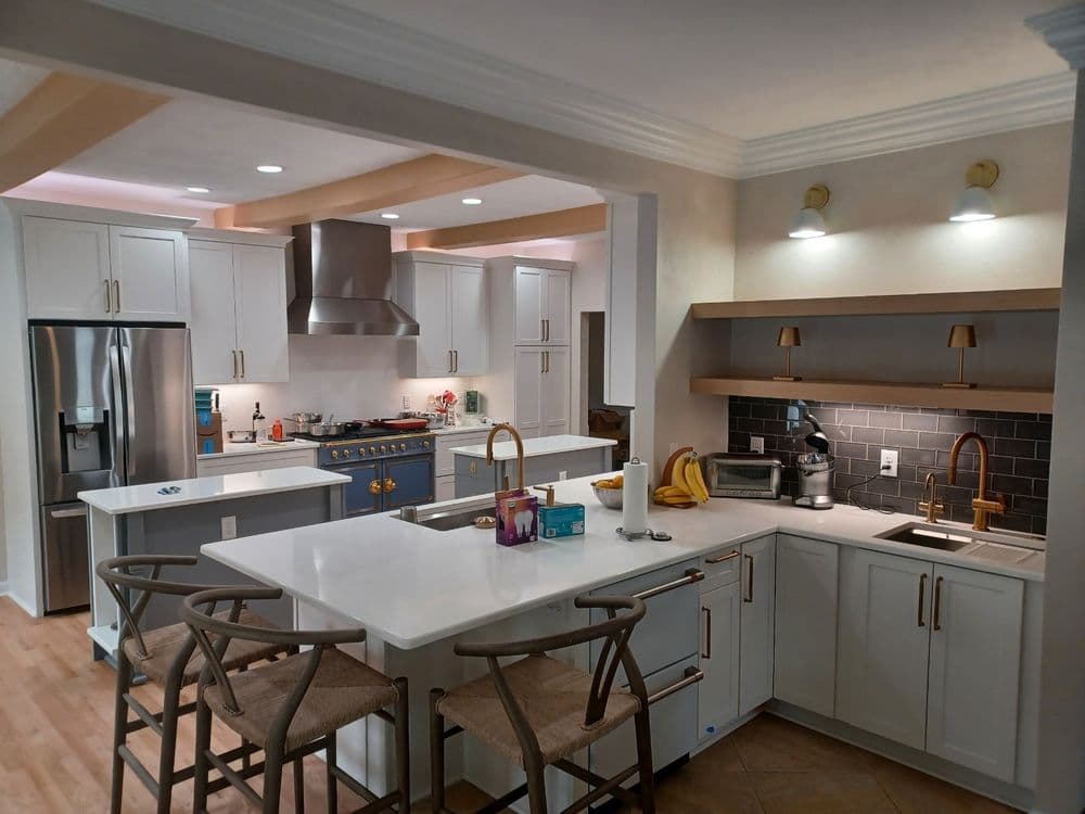 Modern kitchen with white cabinets, stainless steel appliances, and stylish bar stools.