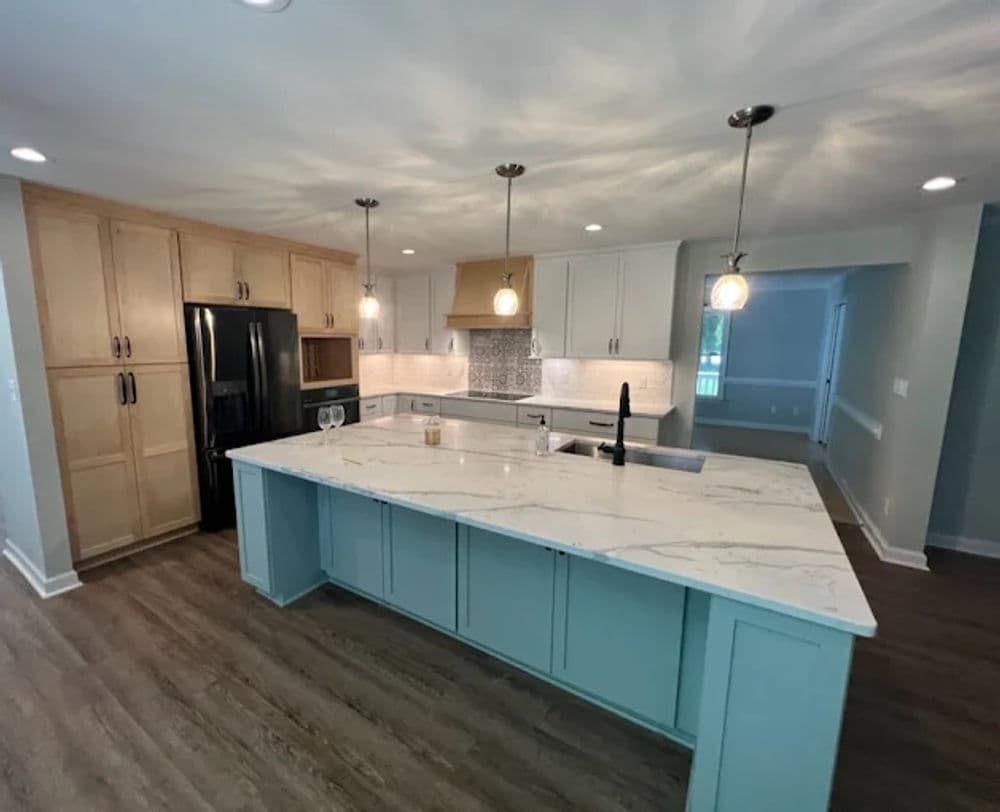 Modern kitchen with quartz island, light wood cabinets, and stylish pendant lighting.